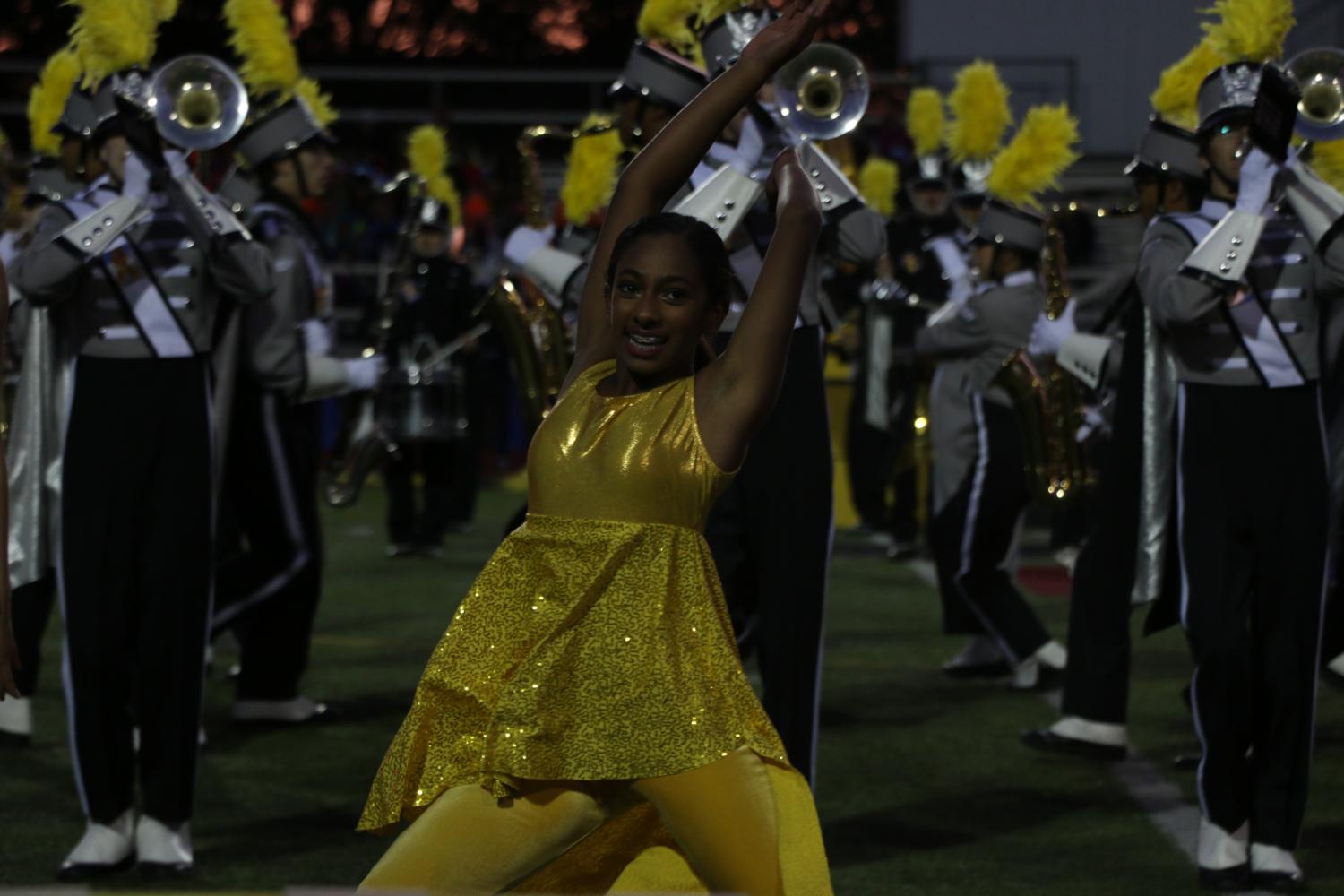 Sliding into a split, freshman Akshaya Suvarna dances with color guard.