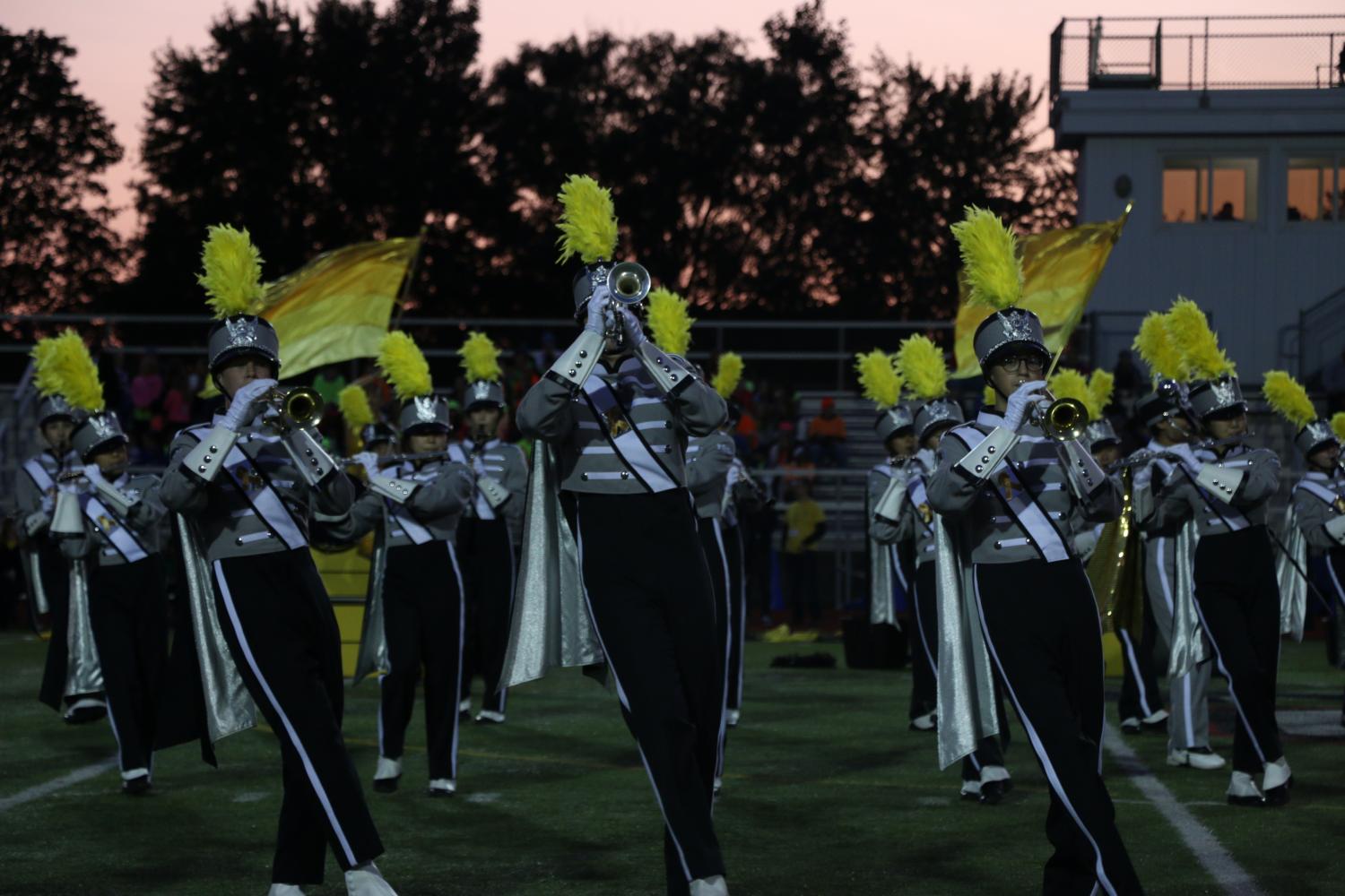 Members of the marching band play trumpets during the football game. 