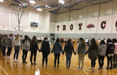RISE members stand hand in hand in a prayer circle before school. 