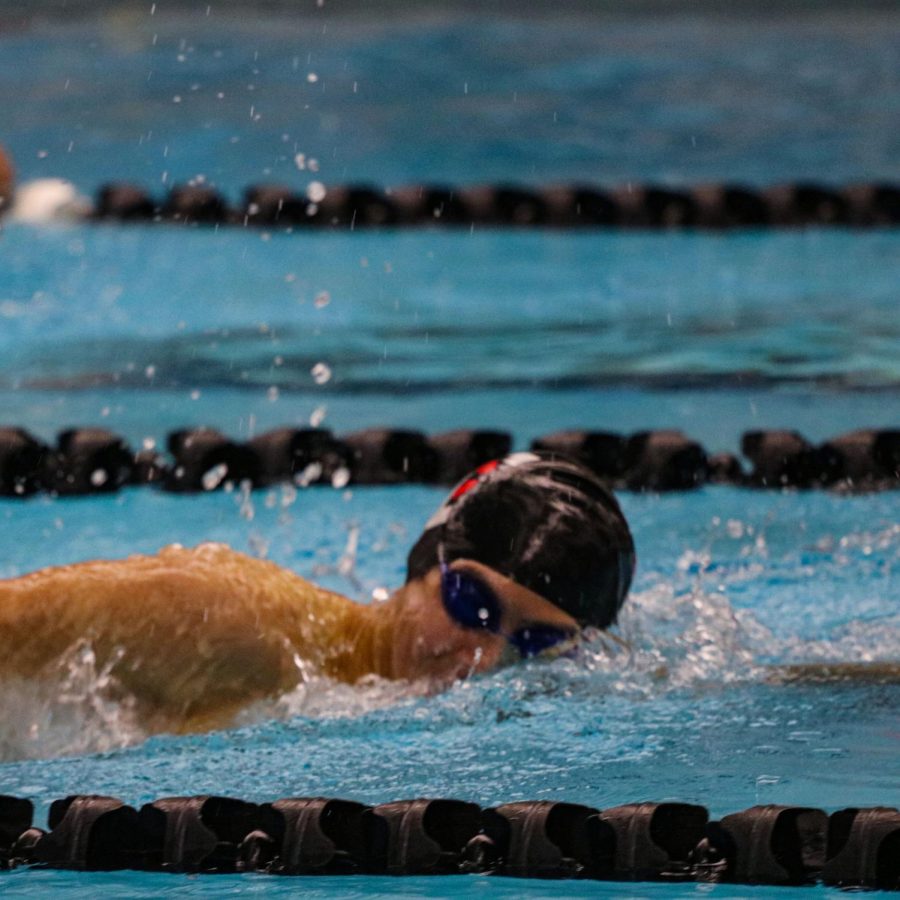 A swimmer smiles as he glides into first place.