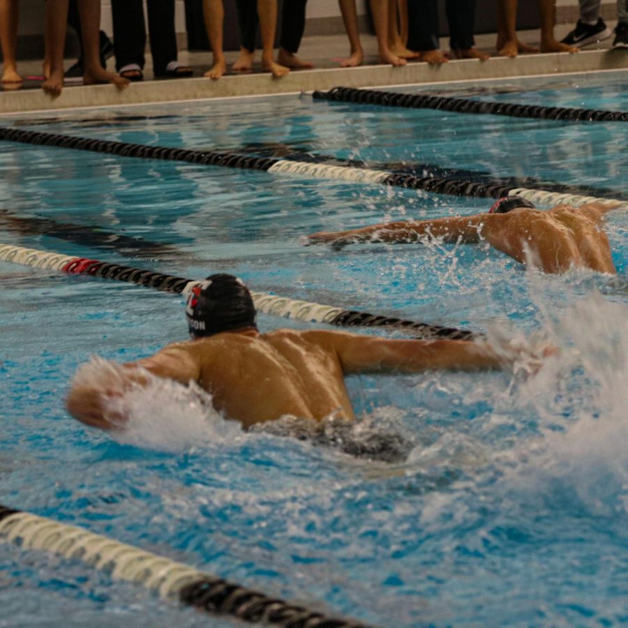 A swimmer from Troy High School and Troy Athens High School race for first place.